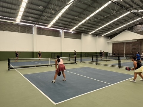 Indoor pickleball action — Skill Split keeps each tier on its own court